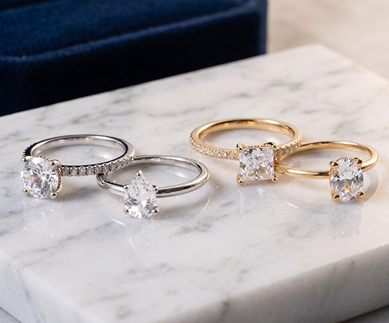 Four Engagement Rings from Rare Carat, placed on a surface, sparkling beautifully